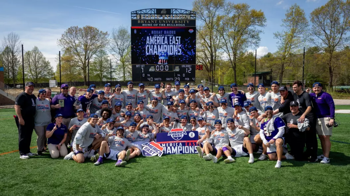 Koleton Marquis and the UAlbany Great Danes team posing in front of Bryant University